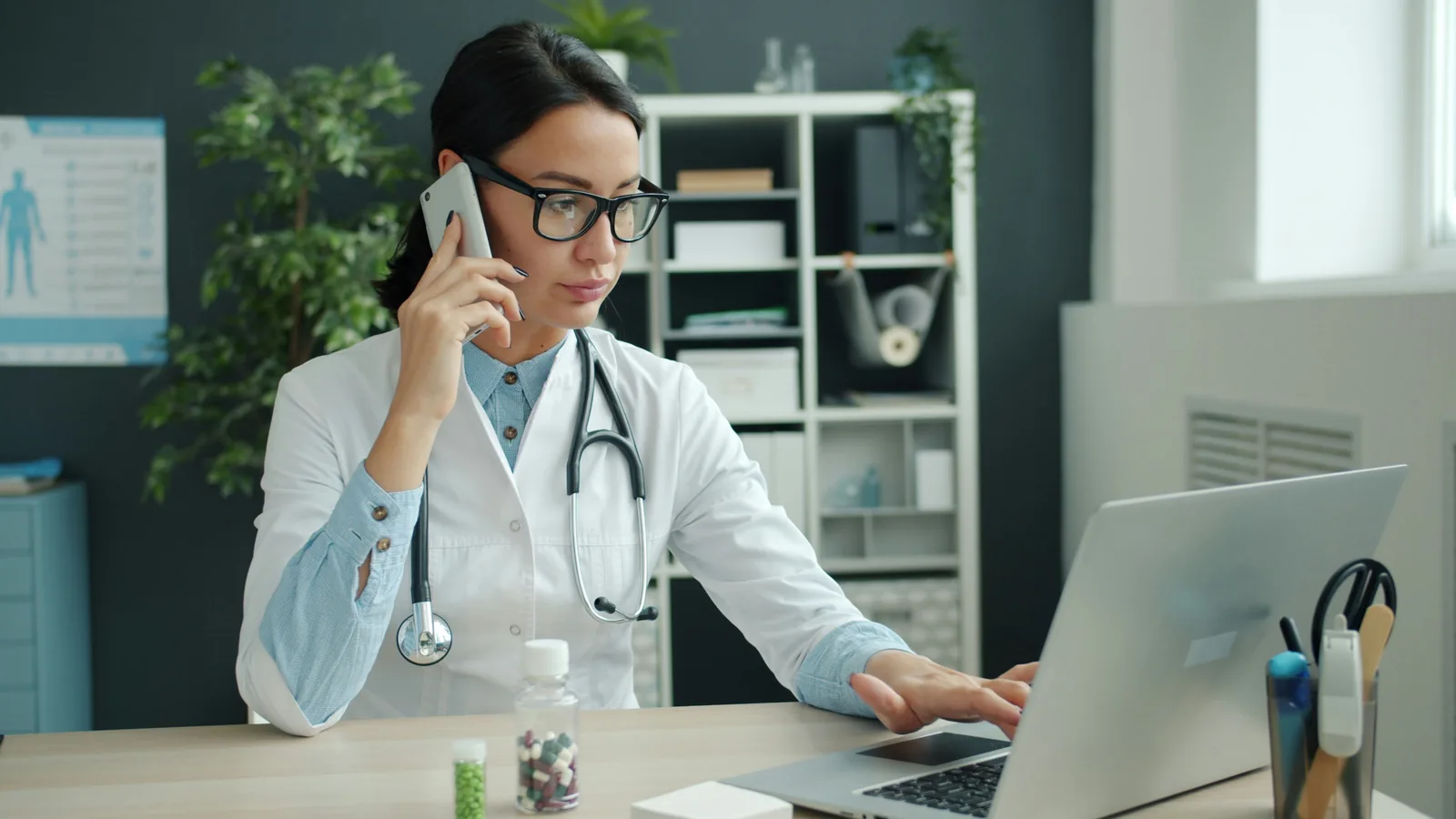 Doctora documentando una consulta médica mientras utiliza una computadora.